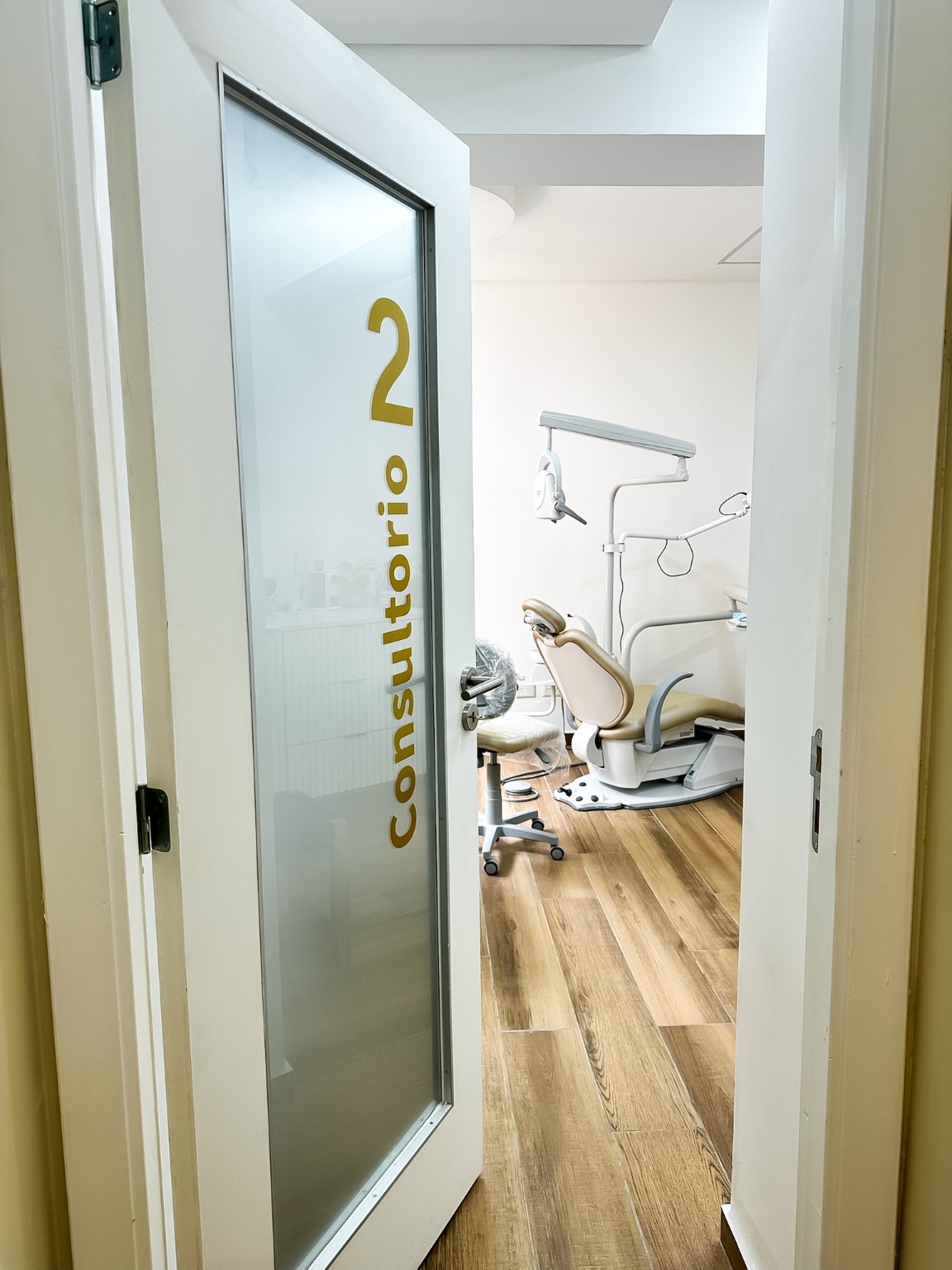 Puerta abierta del consultorio 2, con el sillón y el equipo odontológico a la vista.